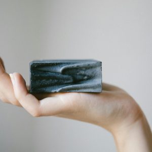 A minimalist image of a hand holding a charcoal soap bar, showcasing clean beauty concepts.