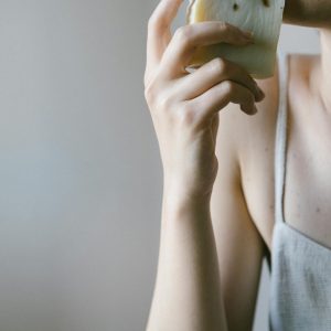 A woman holding artisanal soap, emphasizing natural skincare with eco-friendly elements in a minimalist setting.