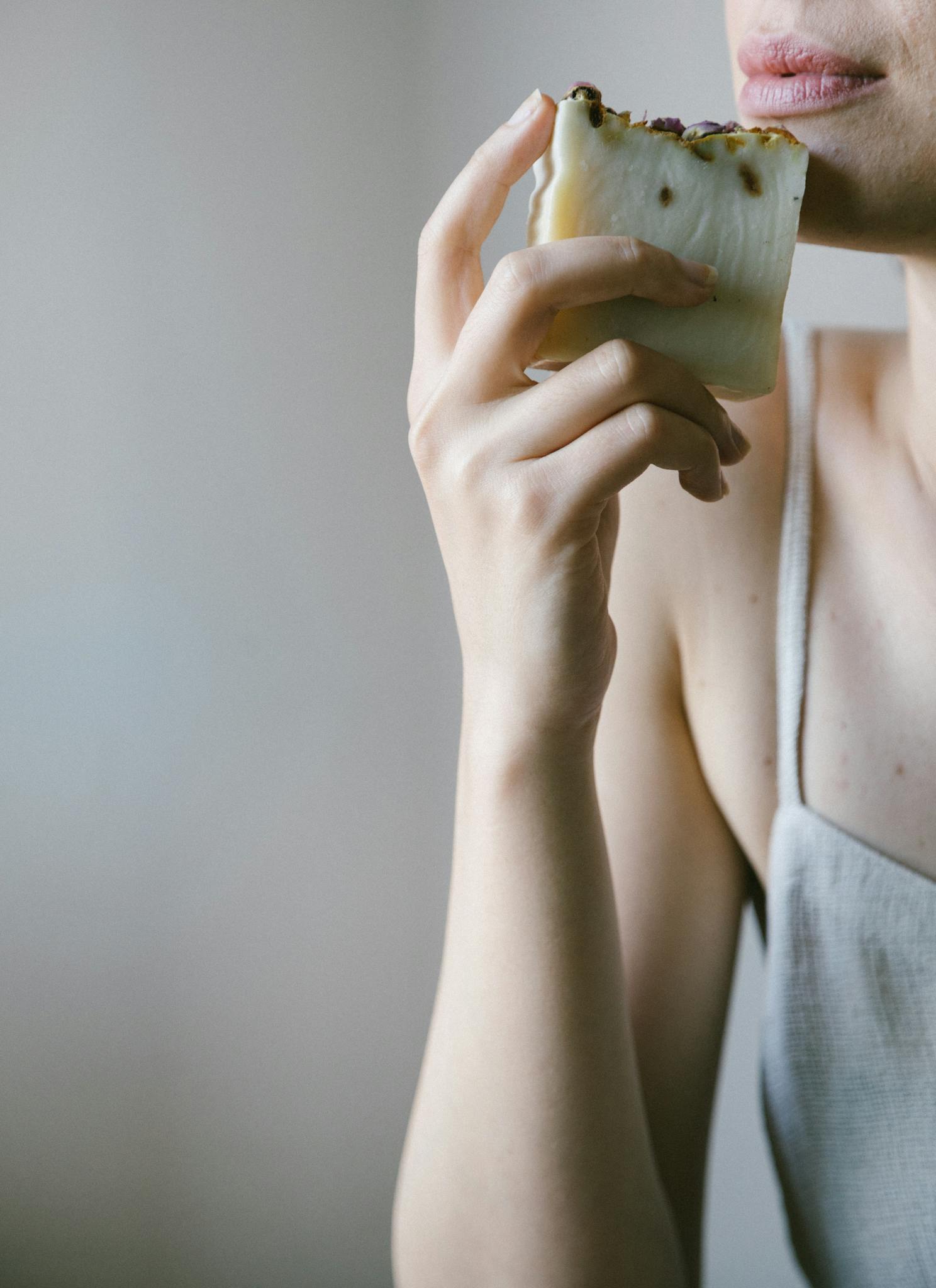 A woman holding artisanal soap, emphasizing natural skincare with eco-friendly elements in a minimalist setting.