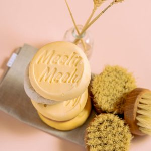 Flat lay of handmade, organic soaps with natural brushes on a pink background.