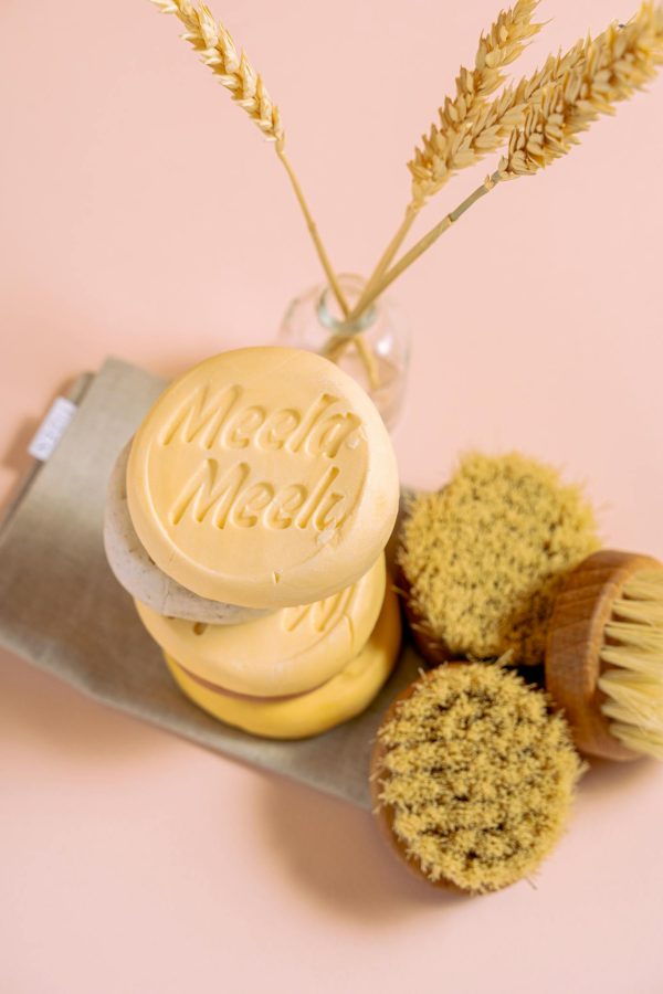 Flat lay of handmade, organic soaps with natural brushes on a pink background.