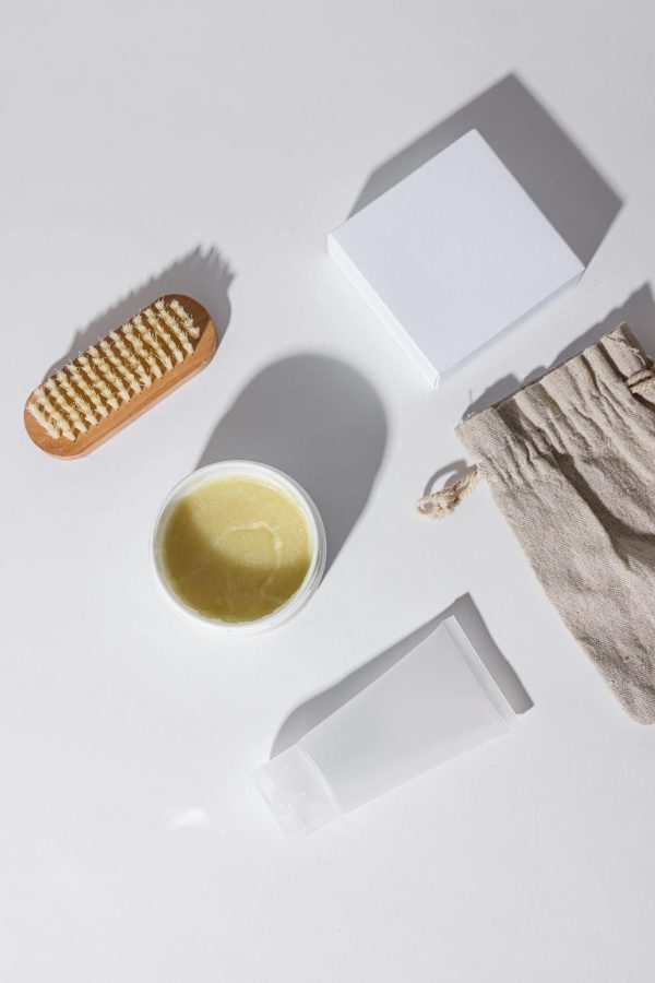 Flat lay of skincare products including a brush, container, and pouch on a white surface.